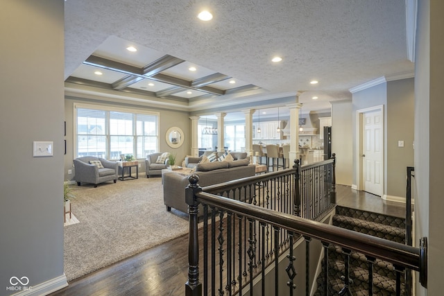 interior space with crown molding, dark hardwood / wood-style flooring, beam ceiling, coffered ceiling, and decorative columns