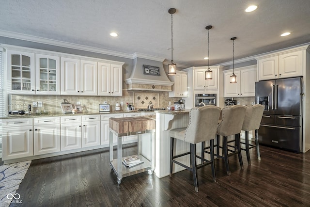 kitchen featuring white cabinets, appliances with stainless steel finishes, decorative light fixtures, tasteful backsplash, and custom range hood