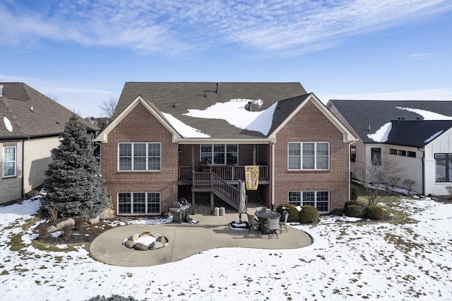 snow covered rear of property with an outdoor fire pit and a patio