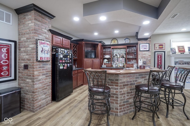 bar featuring black fridge and light hardwood / wood-style flooring