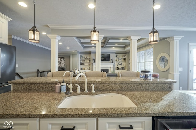 kitchen with pendant lighting, sink, white cabinetry, and ornate columns