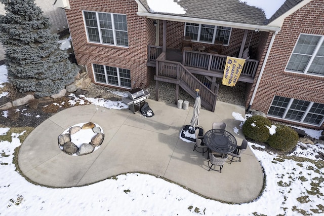 snow covered back of property featuring an outdoor fire pit and a patio