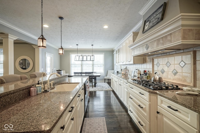 kitchen with sink, a textured ceiling, decorative light fixtures, and dark stone countertops