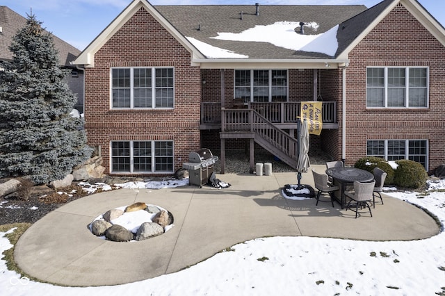 snow covered rear of property featuring an outdoor fire pit and a patio area