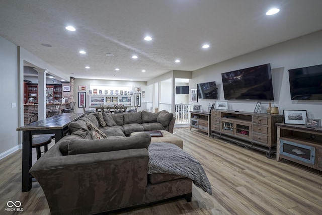 living room with hardwood / wood-style floors, ornate columns, and a textured ceiling