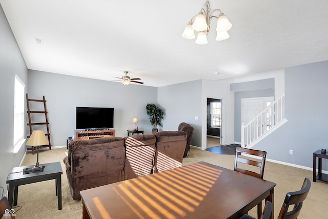 carpeted dining space with ceiling fan with notable chandelier