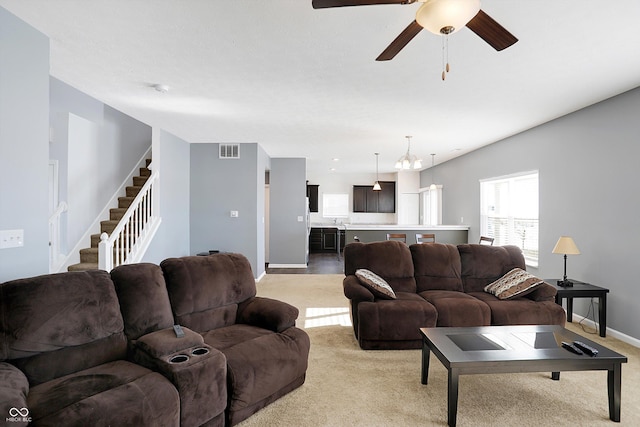 carpeted living room featuring ceiling fan with notable chandelier