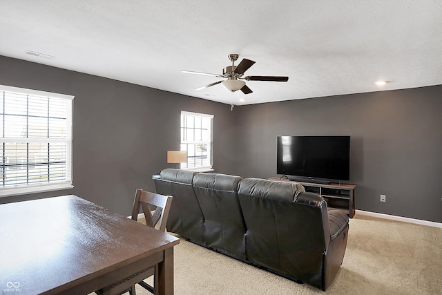 carpeted living room featuring ceiling fan and a wealth of natural light