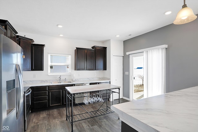 kitchen featuring appliances with stainless steel finishes, decorative light fixtures, sink, plenty of natural light, and dark hardwood / wood-style floors