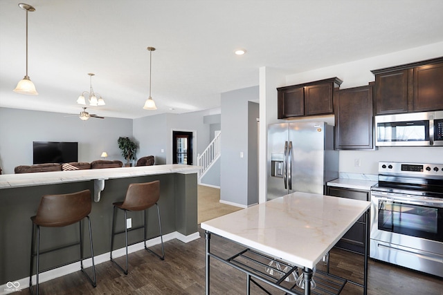 kitchen featuring dark brown cabinetry, a kitchen bar, appliances with stainless steel finishes, and dark hardwood / wood-style flooring