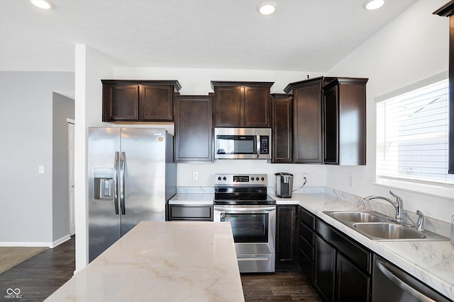 kitchen featuring light stone countertops, appliances with stainless steel finishes, dark wood-type flooring, sink, and dark brown cabinets