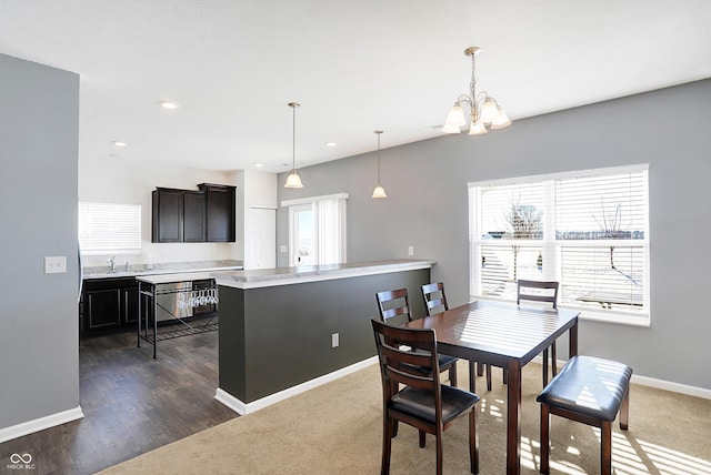 carpeted dining area featuring sink, a chandelier, and a healthy amount of sunlight