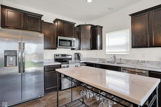 977 Capricorn Dr, Franklin, IN 46131 - kitchen with a sink, dark wood-style floors, light stone countertops, dark brown cabinets, and appliances with stainless steel finishes