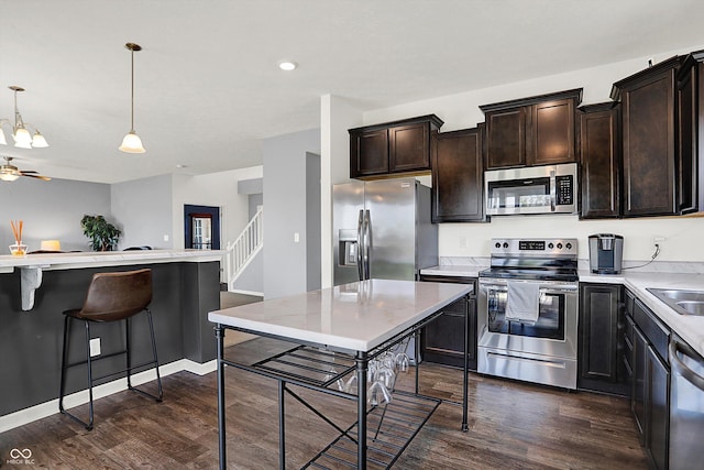 977 Capricorn Dr, Franklin, IN 46131 - kitchen featuring decorative light fixtures, dark brown cabinetry, dark wood-style flooring, light countertops, and appliances with stainless steel finishes