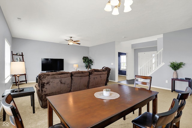 977 Capricorn Dr, Franklin, IN 46131 - dining room featuring carpet, ceiling fan with notable chandelier, stairway, baseboards, and visible vents