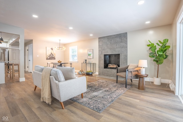 living room with a tile fireplace, hardwood / wood-style flooring, and a notable chandelier