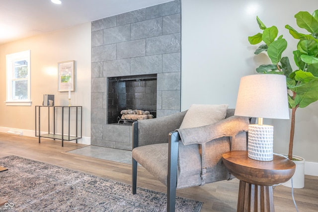 living room with wood-type flooring and a tiled fireplace