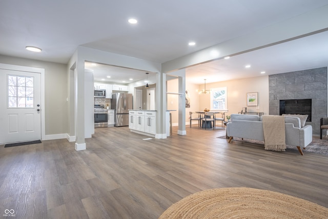 unfurnished living room featuring wood-type flooring and a tiled fireplace