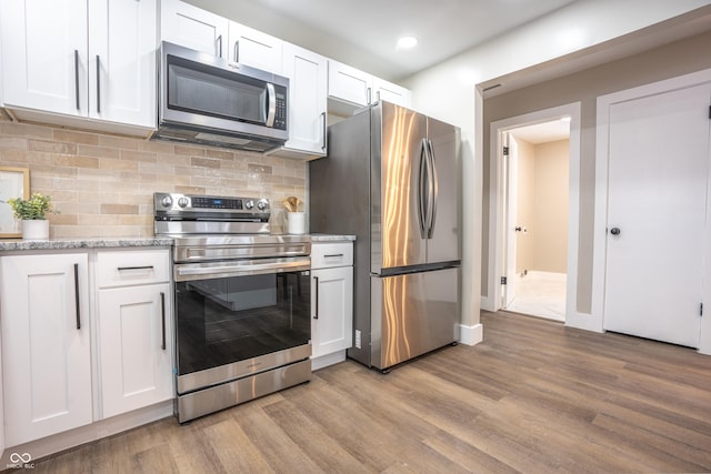 kitchen featuring white cabinets, stainless steel appliances, light hardwood / wood-style flooring, and backsplash