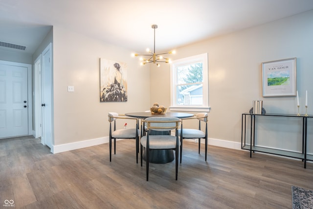 dining space with dark wood-type flooring and a notable chandelier