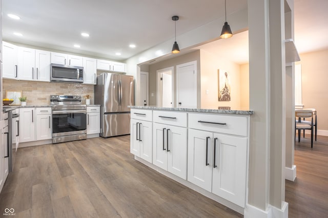 kitchen featuring backsplash, white cabinets, hanging light fixtures, and stainless steel appliances