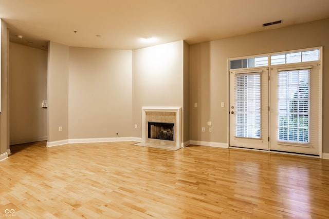 unfurnished living room featuring a high end fireplace and light hardwood / wood-style floors