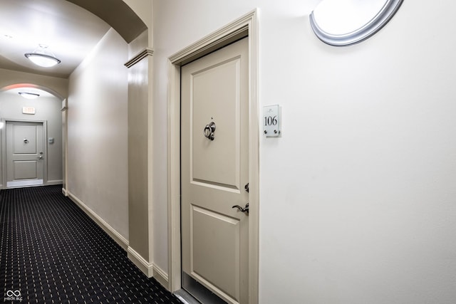 corridor featuring dark colored carpet