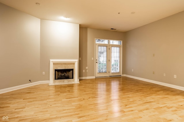 unfurnished living room featuring a premium fireplace and light hardwood / wood-style floors