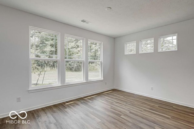 empty room with hardwood / wood-style floors and a textured ceiling