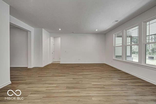 empty room with a textured ceiling and light hardwood / wood-style flooring