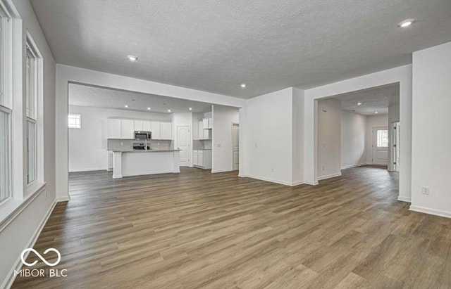 unfurnished living room featuring wood-type flooring and a textured ceiling