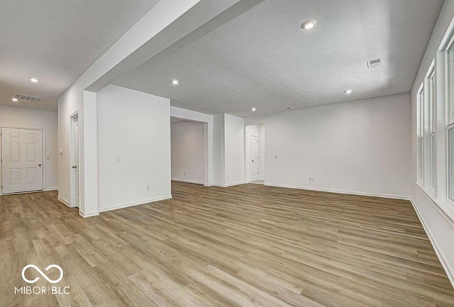 unfurnished living room with light wood-type flooring and a textured ceiling