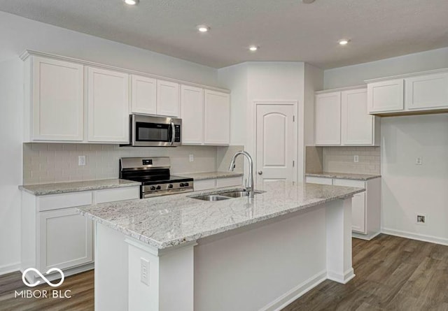 kitchen featuring appliances with stainless steel finishes, white cabinetry, dark hardwood / wood-style flooring, sink, and a center island with sink