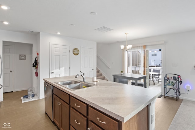 kitchen featuring pendant lighting, dishwasher, light hardwood / wood-style flooring, sink, and a center island with sink