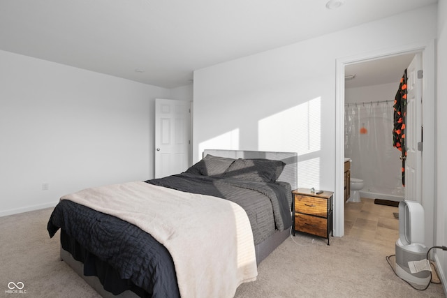 bedroom featuring light colored carpet and ensuite bathroom