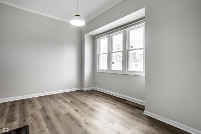 unfurnished room with ornamental molding and light wood-type flooring