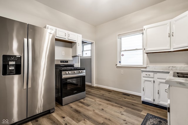 kitchen with wood-type flooring, appliances with stainless steel finishes, and white cabinets