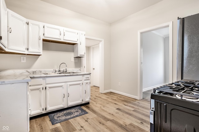 kitchen featuring white cabinetry, light hardwood / wood-style floors, gas range, and sink