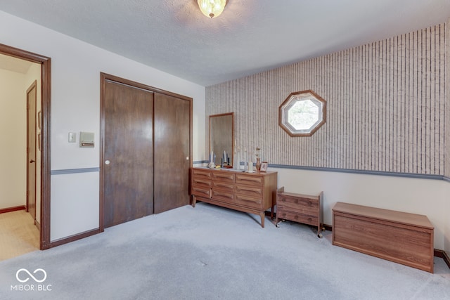 bedroom featuring light carpet, a textured ceiling, and a closet