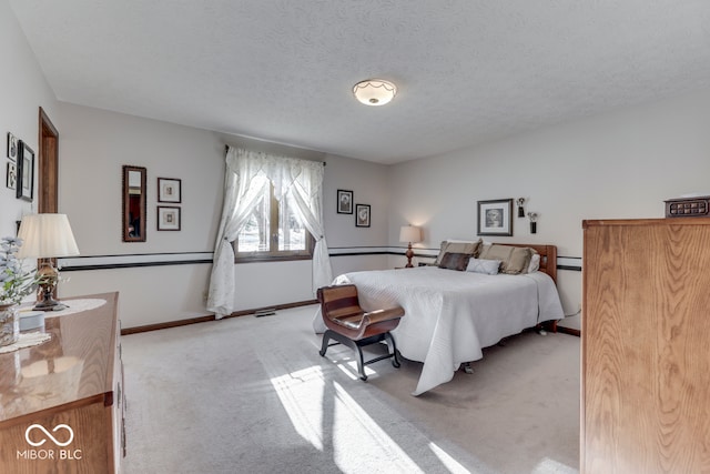 bedroom featuring light colored carpet and a textured ceiling