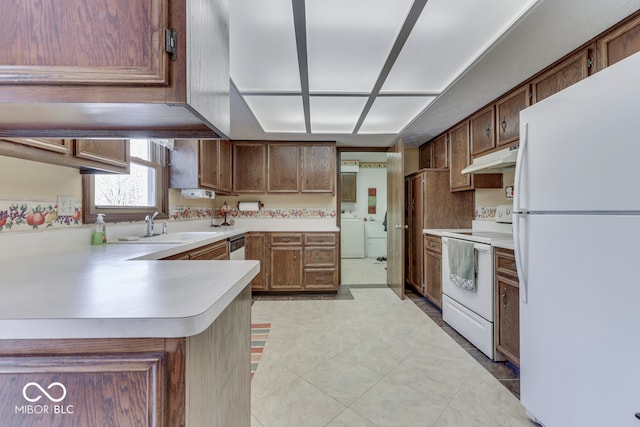 kitchen with sink, white appliances, kitchen peninsula, and independent washer and dryer