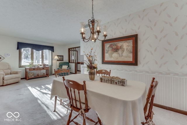 dining room featuring a textured ceiling, an inviting chandelier, and light colored carpet