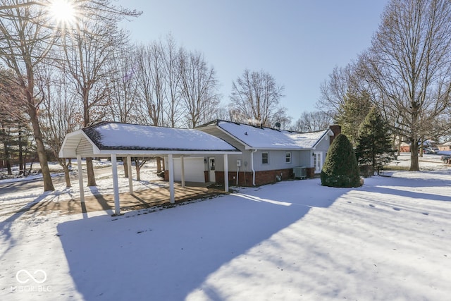 snow covered back of property featuring a garage and cooling unit