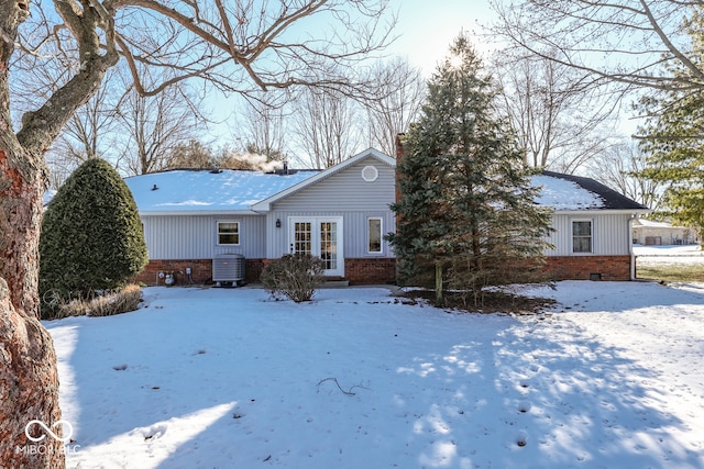 snow covered house featuring french doors and central air condition unit