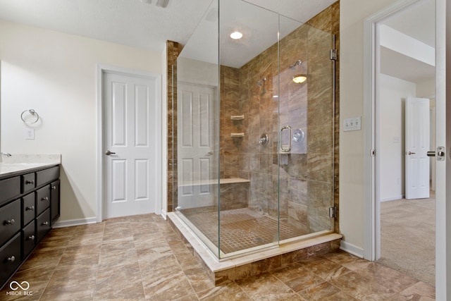 bathroom with a shower stall, baseboards, and vanity