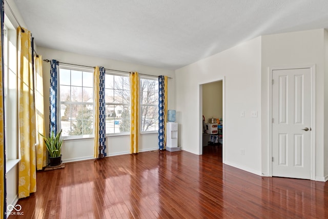 spare room with wood-type flooring and baseboards