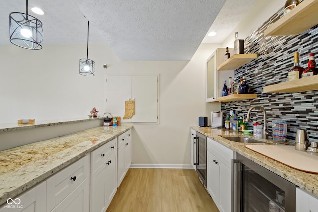 kitchen featuring tasteful backsplash, light wood-style flooring, wine cooler, open shelves, and a sink