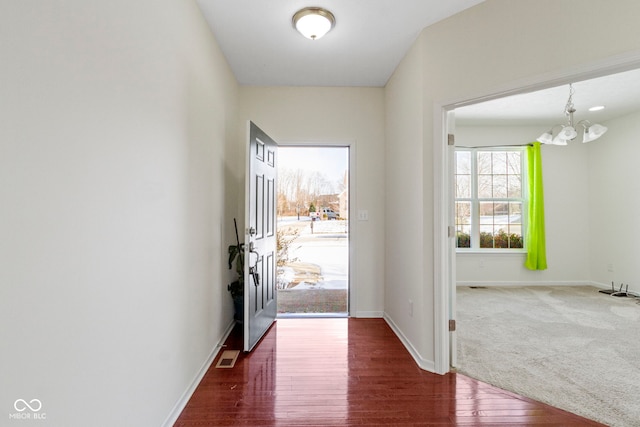 entryway with a chandelier, wood finished floors, visible vents, and baseboards