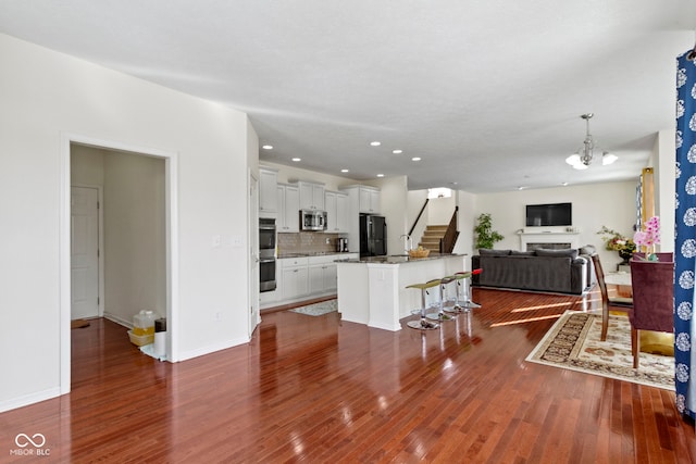 kitchen featuring a breakfast bar area, stainless steel appliances, dark wood-type flooring, and open floor plan