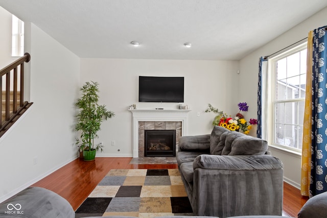 living area featuring plenty of natural light, wood finished floors, and a tile fireplace